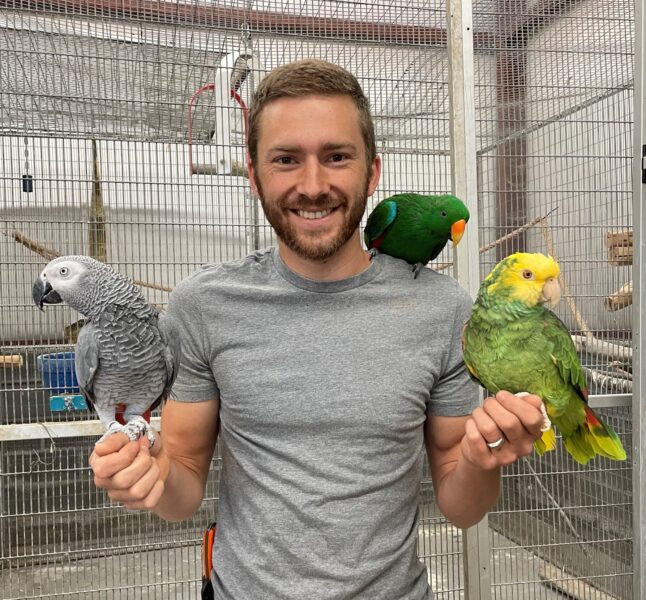 Michael Maughon holding 3 parrots