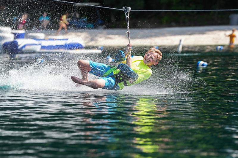 boy on water zipline landing in lake